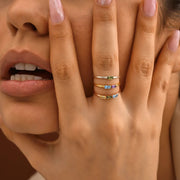 Close-up of a hand wearing multiple baguette birthstone rings with a blurred background